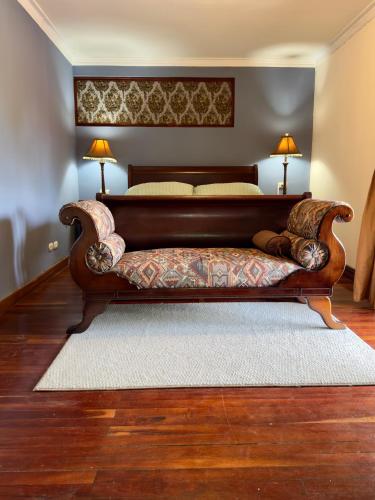 a large bed with a bench in a room at Victorian House in San Isidro