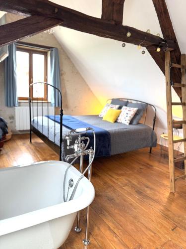 Cette chambre mansardée comprend un lit et une baignoire. dans l'établissement La Grange de Montrésor, à Montrésor
