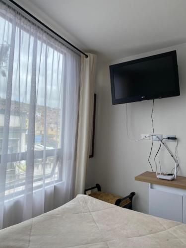 a bedroom with a bed and a window with a television at Apartamento floral in Tunja