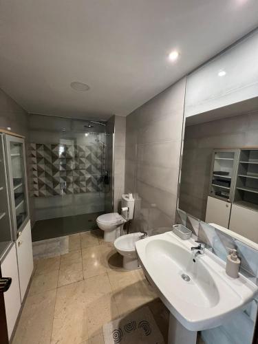 a bathroom with two toilets and a sink and a toilet istg at Piso Super Espacioso en Cambados Centro in Cambados