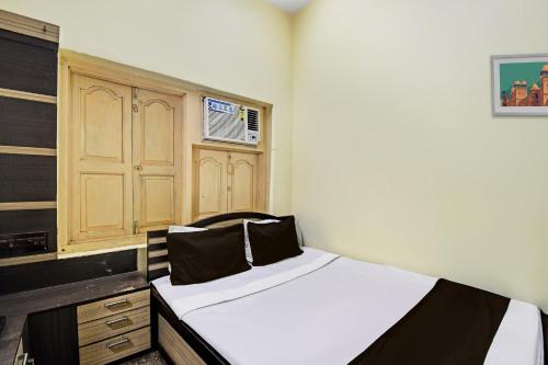 a bedroom with a bed and a wooden cabinet at Hotel O Arati House in Kolkata