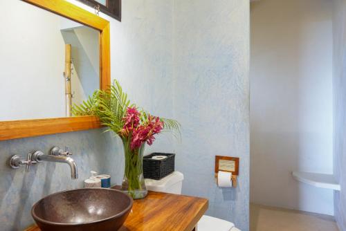 a bathroom with a sink with a vase of flowers at Casa Marbella in Santa Teresa Beach
