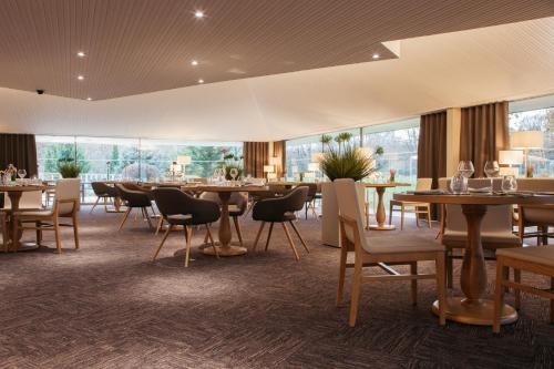 a restaurant with tables and chairs and windows at Best Western Le Bois de la Marche in Poitiers
