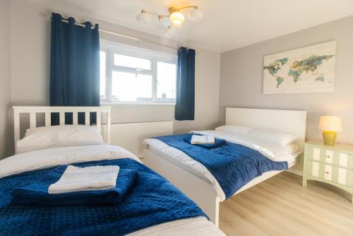 two beds in a room with blue curtains at 4 Bedroom Gateway in Winchester in Winchester