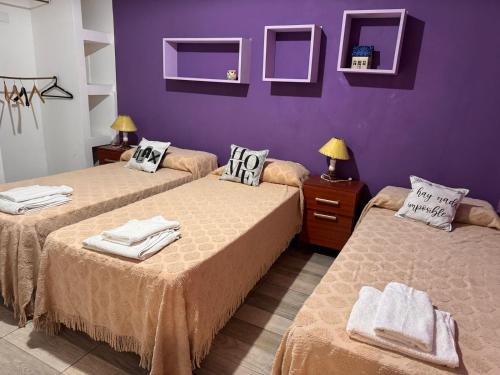 two beds in a room with purple walls at Alojamientos Premiun Centro in Termas de Río Hondo