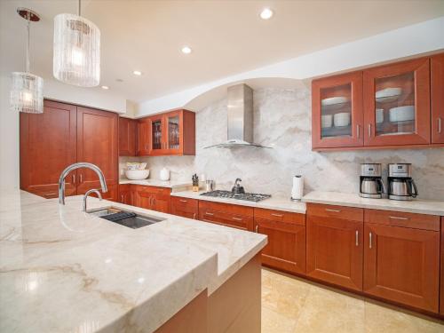 ワイレアにあるWailea's Most Exquisite Ocean Front Luxury Villa - Royal Ilima A201! Newly Renovated!の大きなキッチン(木製キャビネット、シンク付)