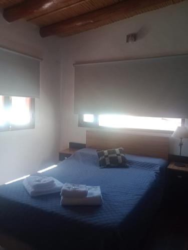 a bedroom with a blue bed with two towels on it at Ipay Alojamiento Familiar in Purmamarca