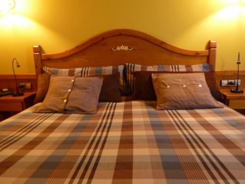a bed with a plaid blanket and two pillows at Petit Hotel in Pas de la Casa
