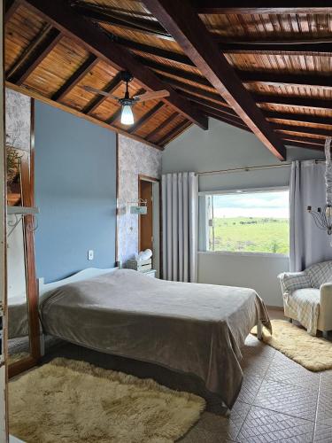 a bedroom with a large bed and a window at Pousada Calu in Cunha