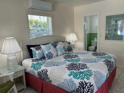 a bedroom with a bed with a blue and white comforter at Bahama Beach Club Pompano - Fort Lauderdale - Charming and Cozy Studios & Apartments close to Beach with Pool in Pompano Beach