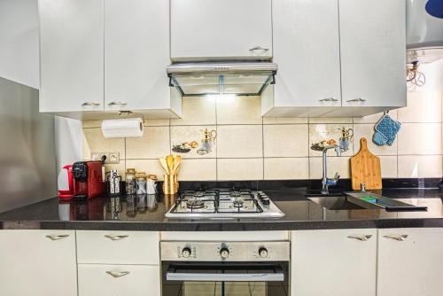 a kitchen with white cabinets and a stove top oven at Chic & Cozy Retreat in Agadir in Agadir