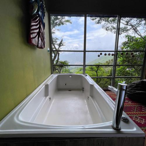 a bath tub in a room with a large window at ANCESTRAL GLAMPING in Barbosa