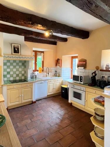 - une grande cuisine avec des armoires et des appareils blancs dans l'établissement La grande maison dans la prairie, à Bonnemain