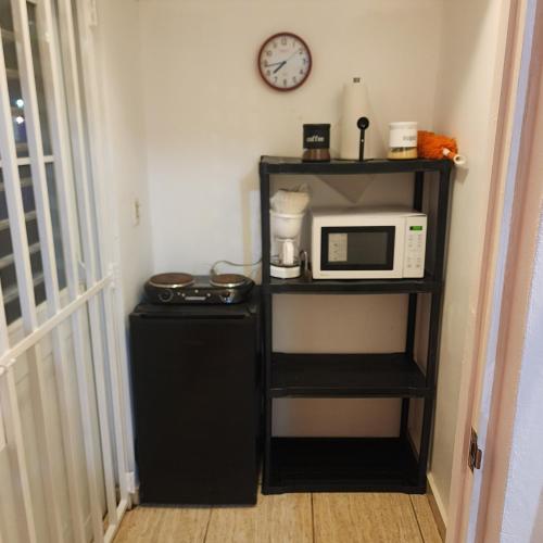 a kitchen with a microwave and a refrigerator and a clock at Cozy & comfortable crib in Carolina