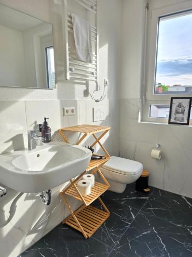 a bathroom with a white sink and a toilet at Design-Apartments I Klimaanlage I Boxspring I Nespresso I Parklplatz in Weil am Rhein