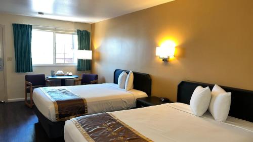 a hotel room with two beds and a table at Black Canyon Motel in Montrose