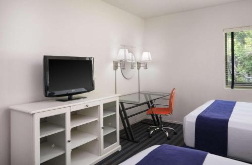 a hotel room with a desk with a tv and a bed at Hotel Zico, BW Signature Collection in Mountain View