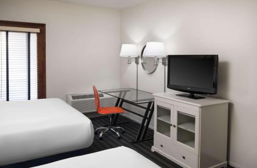 a hotel room with a bed and a desk with a television at Hotel Zico, BW Signature Collection in Mountain View