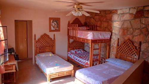 a bedroom with two bunk beds and a stone wall at Casa YilZil in Alpuyeca