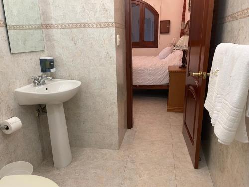 a bathroom with a sink and a toilet and a bed at Casa del León in Oaxaca City