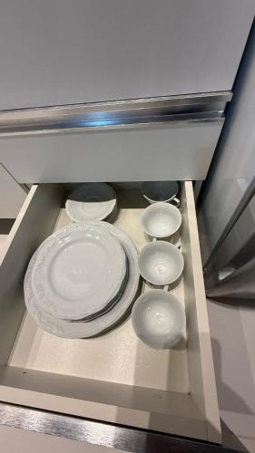 a group of white plates in a drawer at Seminate Apartamento in Franca