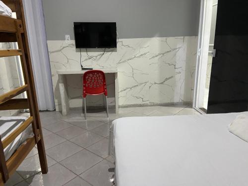 a room with a red chair and a desk and a television at Hotel e Pousada REQUINTTE in Parnaíba