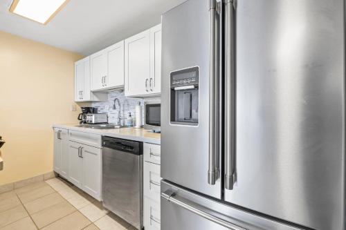 a kitchen with white cabinets and a stainless steel refrigerator at Amazing Beachfront Condo by Pool in Hauula