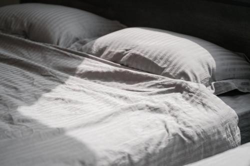 an unmade bed with white sheets and a pillow at 新築オーシャンビュー離れ FLAG Awaji HANARE in Awaji