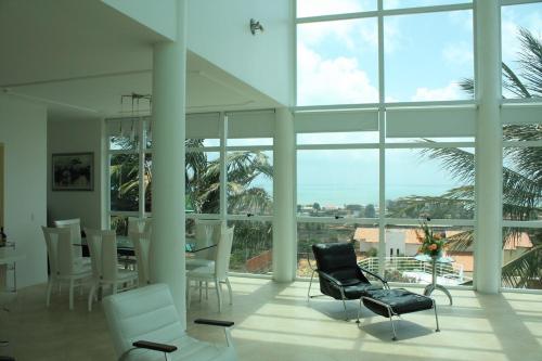a living room with chairs and a table and windows at Luxury Mansion in Porto das Dunas in Aquiraz