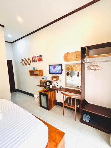 a bedroom with a bed and a desk and a tv at Luang Prabang Museum Inn in Luang Prabang