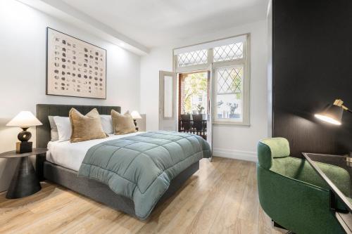 a bedroom with a bed and a green chair at Simpson Street Apartments by Urban Rest in Melbourne