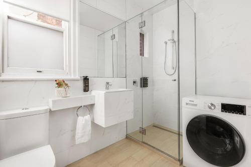 a white bathroom with a washing machine and a glass shower at Simpson Street Apartments by Urban Rest in Melbourne