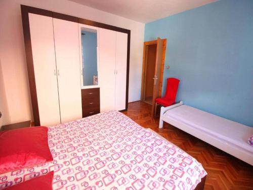 a bedroom with a bed and a red chair at Apartment in Dinji ka by the Beach in Dinjiška