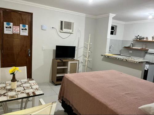 a room with a bed and a table with a tv at Villa Velha Flats in Itamaracá