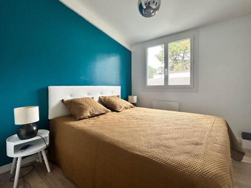 une chambre avec un grand lit avec un mur bleu dans l'établissement Villa rénovée à La Palmyre pour 6 pers. - Patio, wifi, proche plage et commerces - FR-1-705-85, aux Mathes