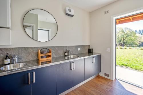 a kitchen with blue cabinets and a mirror at Blue Mountain Lake Lodge and Lake House Fairlie in Fairlie