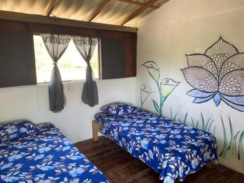 a room with two beds and a wall with flowers at Shanti Lanka Ashram in Guayabas