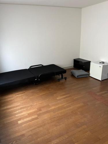 a bed in an empty room with a wooden floor at ドエルノースポイント in Aomori