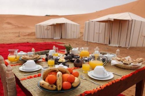 a table with food and drinks in the desert at Nada luxury desert camp in Merzouga