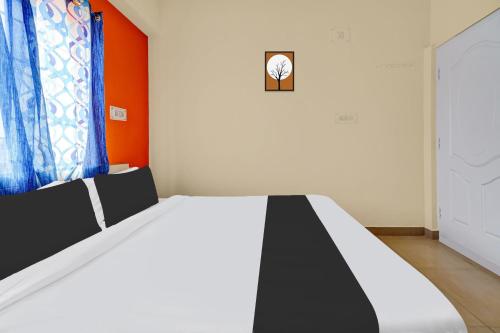 a bedroom with a black and white bed with an orange wall at Super Hotel O Royal Rooms in Bengaluru
