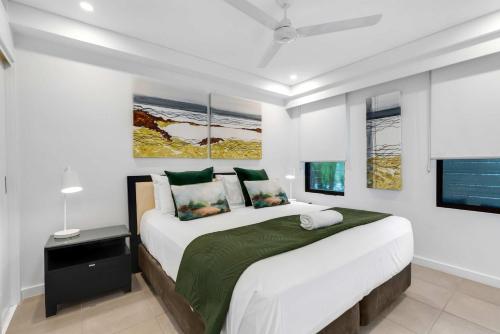 a white bedroom with a large bed and a window at Temple Breeze - Swim Out Apartment in Port Douglas