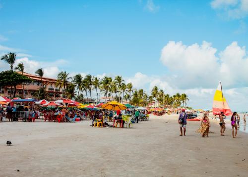 a group of people standing on a beach with umbrellas at Praia do Frances - Casa Vista para o Mar - 50 metros da areia da praia in Praia do Frances