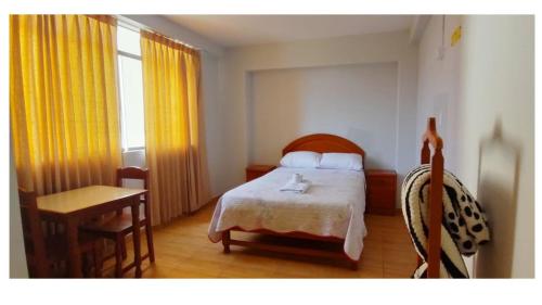 a bedroom with a bed and a table and a desk at Hospedaje La Cascada in Tacna