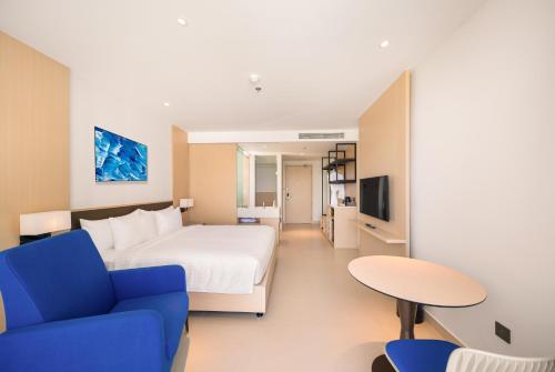 a hotel room with a bed and a blue couch at The Empyrean Cam Ranh Beach Resort in Cam Ranh