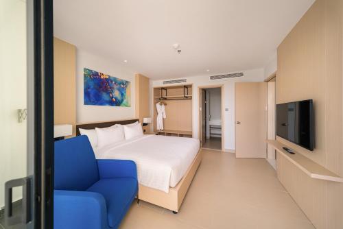 a hotel room with a bed and a blue chair at The Empyrean Cam Ranh Beach Resort in Cam Ranh