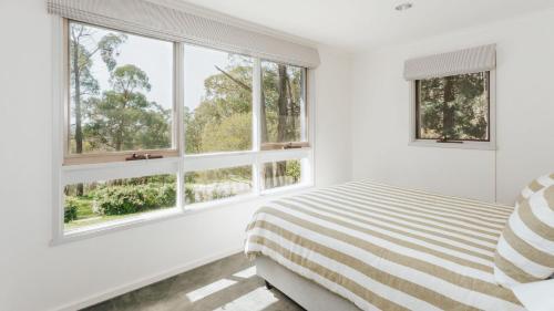 a white bedroom with windows and a bed at Forest Hideaway in Red Hill South