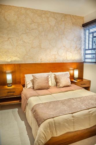 ein Schlafzimmer mit einem großen Bett und zwei Nachttischen in der Unterkunft Bonito Departamento en Tulum in Tulum