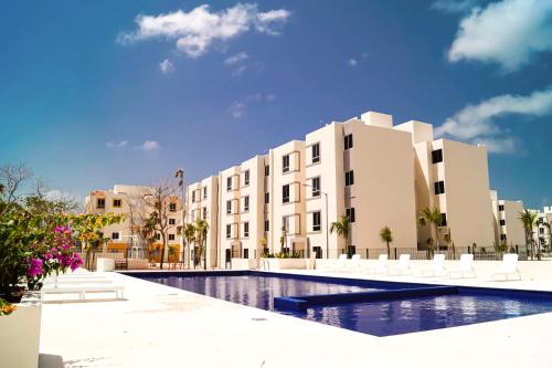 a hotel with a swimming pool in front of a building at Bonito Departamento en Tulum in Tulum