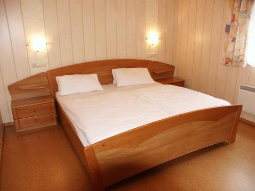 a large wooden bed in a room with two pillows at Gästehaus Leithen in Bad Birnbach
