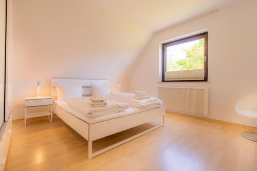 a white bedroom with a bed and a window at Wohnung-D-306 in Böhl